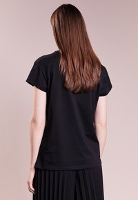 Černé tričko s krátkým rukávem a kulatým výstřihem, volného střihu, s hladkou texturou, jednoduchým designem a minimálním zdobením.