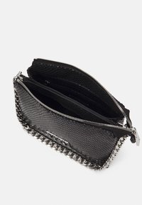 Sac à main synthétique noir texturé avec des accents en chaîne argentée, doté d'une fermeture éclair et de plusieurs compartiments internes pour l'organisation.