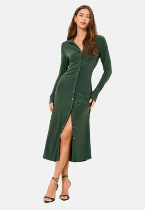 Zöld, hosszú ujjú, gombos ruha sima anyagból; combközépig érő hasítékkal és aranyszínű gombdíszítéssel az elején.