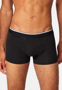 Shorts de boxeur noirs avec un design ajusté, taille élastique avec une bande grise, texture de tissu douce et détail de poche à l'avant.