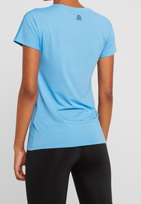 Ljusblå kortärmad träningsskjorta med en texturerad väv, med en liten Reebok-logotyp vid den bakre halsringningen.