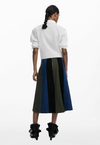 Mehrfarbiger Maxikilt mit vertikalen Paneelen in Denim-Blau, Olivgrün und Schwarz. Der Stoff hat eine glatte Textur.