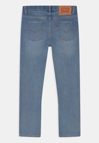 Ljusblå denimjeans med rak skärning, fem fickor och en beige etikett på midjan. Slät textur och minimal blekning.