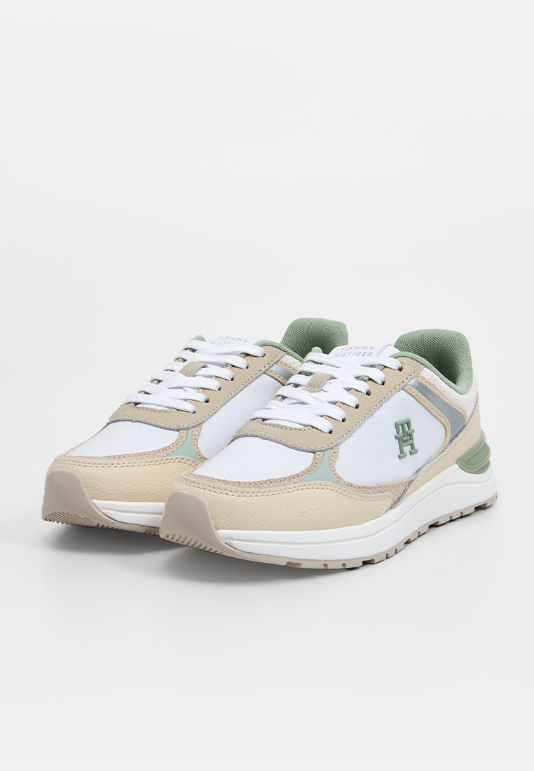 Weiße und beige Sneaker mit grünen Akzenten. Aus Leder und Mesh-Material, runder Zehenbereich, gepolsterter Kragen und Schnürsenkel. Logo an der Seite.