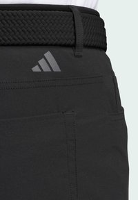 Crne kratke hlače sa teksturiranim tkanim crnim remenom. Sadrže diskretni sivi Adidas logo i šavove, kao i funkcionalne džepove.