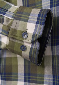 Grün- und blauen karierter Hemd mit einem geknöpften Manschette mit dunklen Knöpfen, aus Baumwollstoff und mit glatter Textur. Die Muster bestehen aus Streifen und Quadraten.