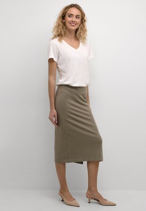 Khaki Midi-Rock mit figurbetontem Design aus weichem Stoff, kombiniert mit einem weißen T-Shirt mit kurzen Ärmeln und V-Ausschnitt sowie nude Farbigen Absatzschuhen.