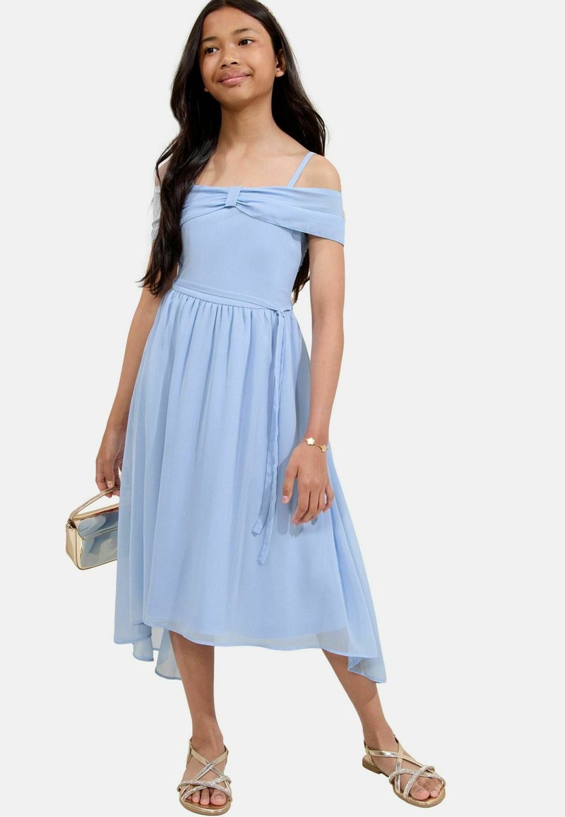 Robe bleu clair à épaules dénudées avec un détail de nœud à l'avant, tissu fluide, jupe plissée et ourlet asymétrique, accompagnée de sandales dorées.