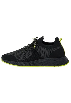 Baskets de sport noires et grises avec semelle noire et accents vert néon, dessus tricoté, design lacé et languette à l'arrière.