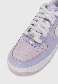 Tenisky Nike Air Force 1 s lilavým lakovaným zvrškom, bielymi šnúrkami, perforovanou špičkou a striebornou ozdobnou značkou s nápisom "AF1 82."