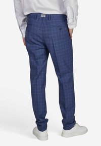 Donkerblauwe geruite broek met een zachte textuur, voorzien van twee achterzakken en een slim fit, gecombineerd met witte sneakers.