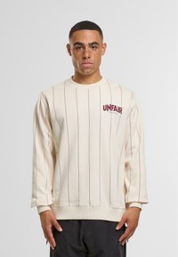 Kreme sweatshirt s vertikalnim bordo prugama, okruglim izrezom i logotipom "UNFAIR ATHLETICS". Ima duge rukave i rebraste manžete.