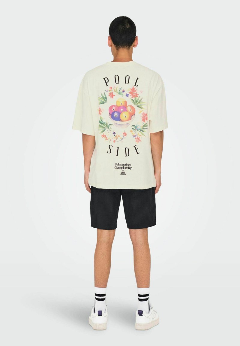 Camiseta blanca de manga corta con un gráfico de un tazón de bolas de billar de colores. El texto dice "POOL SIDE" en negro con acentos florales.