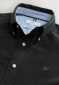 Schwarzes Hemd mit Knopfleiste in regulärer Passform, mit einem hellblauen, gestreiften Kragenfutter und einem kleinen gestickten Logo auf der Brust.