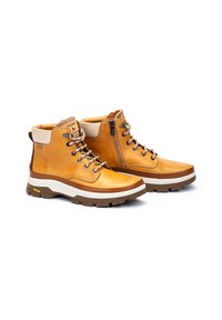 Botas de senderismo de cuero marrón con suelas de goma blancas y marrones, ojales de metal y un zip lateral para un acceso fácil. Presenta un collar acolchado.