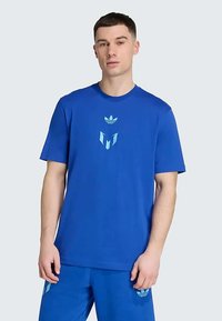 Μπλε βαμβακερό μπλουζάκι με κοντά μανίκια. Περιέχει ένα γραφικό λογότυπο σε ανοιχτό μπλε στο κέντρο και στρογγυλή λαιμόκοψη.