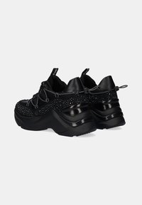 Zapatillas negras con un upper texturizado y embellishments de rhinestones, suela gruesa y cordones elásticos. Acentos negros lisos en el talón.