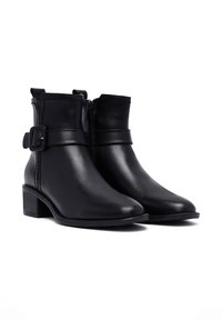 Bottines noires en cuir avec un bout arrondi, fermeture éclair latérale et une sangle décorative avec une boucle. Petit talon carré et texture lisse.