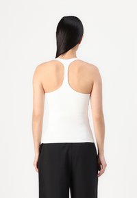 Wit strakke tanktop met een racerback ontwerp, gemaakt van soepele stof, met een strakke silhouet en minimalistische stijl.