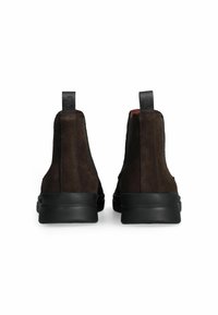 Stivaletti in suede marrone con suole in gomma nera, dotati di pannelli elastici laterali e linguette posteriori per una facile calzata.