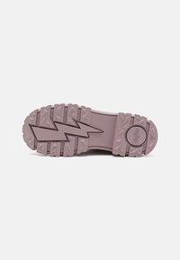Talpă din cauciuc violet cu model în zigzag și crampoane triunghiulare. Logo embosat circular pe călcâie. Design plat și lat pentru stabilitate.
