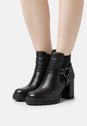 Black leather ankle boots with a textured finish, featuring a side buckle strap and a chunky heel. Rugged rubber sole for traction.