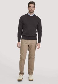 Donkergrijze trui met een ronde hals, gedragen over een lichtblauw overhemd met kraag, gecombineerd met lichtbeige pantalons en crèmekleurige sneakers.