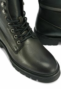 Czarne skórzane buty z fakturowaną powierzchnią, metalowymi elementami, okrągłym noskiem i wytrzymałą podeszwą. Wyposażone w sznurowadła oraz wyściełany kołnierz dla wsparcia.