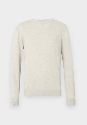 Beige trui met lange mouwen en ronde hals, voorzien van ribbels aan de mouwen en onderkant, gepresenteerd tegen een eenvoudige witte achtergrond.