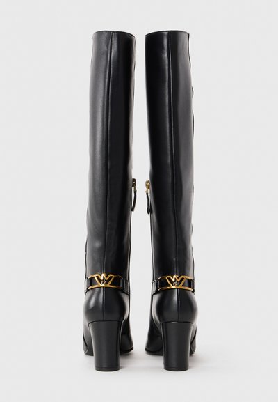 Knee-high black leather boots with a high block heel, featuring a gold logo accent and side zipper for ease of wear. Smooth texture.