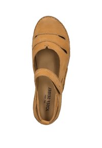 Zapato de cuero marrón claro con diseño troquelado, correa sobre el pie, punta redondeada y detalles de costura. La plantilla interior es de color beige con marca.