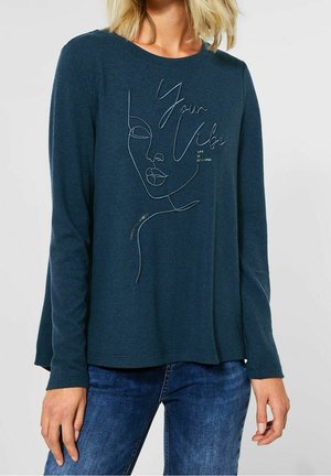 Türkisfarbenes Langarmshirt mit runder Ausschnitt, das auf der Vorderseite weiße Linienstreifen-Kunst eines Gesichts und den Text "Your Vibe" zeigt. Weiche Textur.