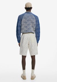 Cămașă bărbați, albastră, cu imprimeu, cu mâneci lungi texturate, asortată cu pantaloni scurți crem, cu un design geometric subtil și un buzunar aplicat.