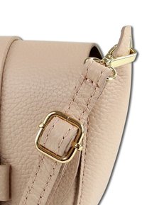 Beige leren handtas met een ronde vorm, een gestructureerd oppervlak en een metalen sluiting in goudkleur met een rechthoekige gespdetail.