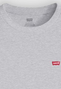 Grå bomulds T-shirt med rund hals og korte ærmer. Har et lille rødt Levi's-logo på venstre brystområde. Glat tekstur.