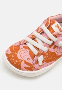 Textilsneaker med ett mönster av rosa och orange katter, vita snören och gummisula. Runt tåparti med stickade detaljer.