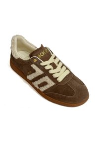 Sneaker in suede marrone con accenti in pelliccia crema, lacci crema e dettagli del logo dorato. Presenta una suola in gomma e un design della punta distintivo.