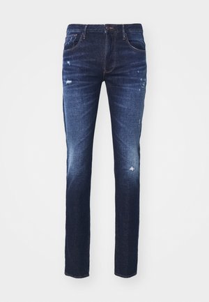 Tmavě modré džíny se slim fit, s opotřebenými detaily a rovnými nohavicemi. Klasický design s pěti kapsami a poutky na pás.