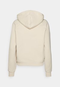 Sudadera con capucha de color beige, con un ajuste corto, puños acanalados y costuras planas. Textura suave y diseño minimalista, adecuada para uso casual.