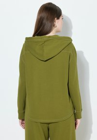 Olivově zelená mikina s kapucí, vyrobená z texturované ribbed tkaniny, s dlouhými rukávy a uvolněným střihem, s viditelnými švy a zakřiveným lemem.