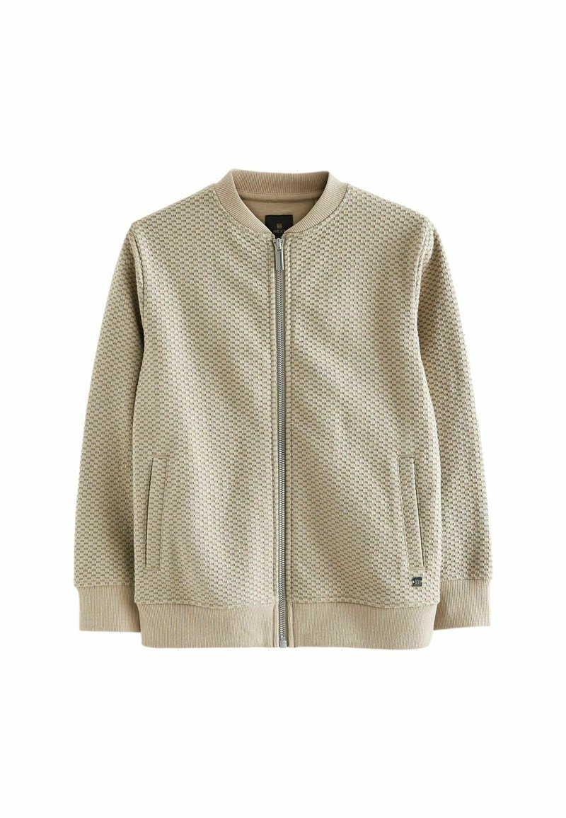 Veste bomber beige texturée avec une fermeture éclair à l'avant, des poignets côtelés et deux poches latérales. Comprend un col rond et des détails de design minimalistes.