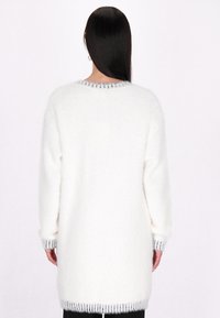 Weißer, flauschiger Pullover mit langen Ärmeln, rundem Halsausschnitt und grauen gestreiften Details an den Bündchen und am Saum. Weiche Textur und lockere Passform.