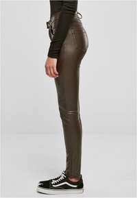 Bruine neplederen skinny broeken met een hoge taille, zijzakken en accentstiksels, gecombineerd met zwart-witte veterschoenen.