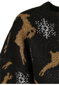 Pull noir en tricot avec des motifs de rennes dorés et de flocons de neige blancs, montrant la texture et un col rond côtelé.