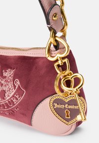 Borsa a mano in suede viola e pelle rosa con hardware dorato, portachiavi a forma di cuore e logo Juicy Couture su un'etichetta a forma di cuore.
