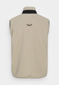 Gilet en polaire beige avec col noir, sans manches, surface texturée et une simple couture verticale accentuée à l'arrière.