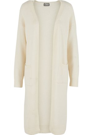 Long, open-front cardigan in soft cream-colored fabric. Features two front pockets and ribbed cuffs. Simple, minimalistic design.