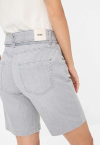 Grijze denim shorts met een hoge tailleband, een rechthoekig merkembleem, twee achterzakken en een gladde textuur.
