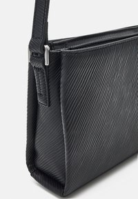 Borsa a tracolla nera con texture e un motivo rigato diagonale, caratterizzata da una forma piatta e strutturata e accessori in argento sulla tracolla regolabile.
