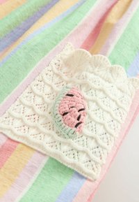Tissu rayé aux couleurs pastel, avec un patch en crochet blanc texturé et un emblème de pastèque rose-vert.